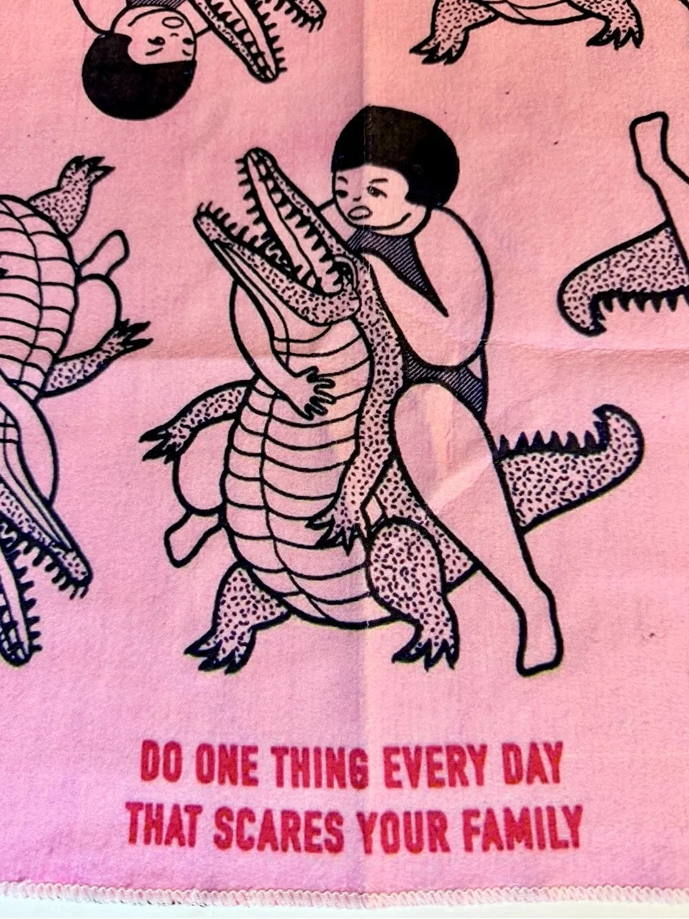 Funny pink dish / tea towel with a repeating print of a person wrestling an alli